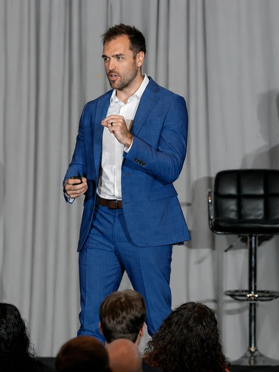 Nick Fischer, founder of CHIROBASIX, speaking on stage at a chiropractic marketing event.